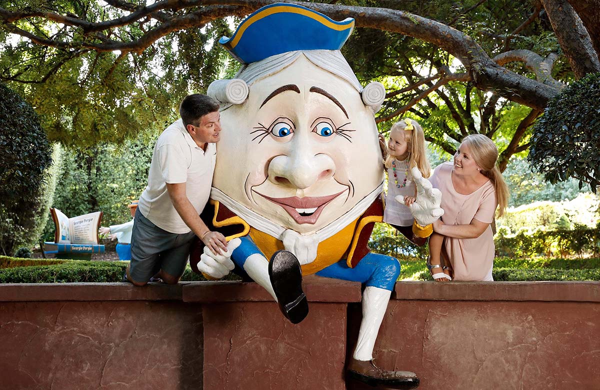 A mom, dad, and daughter with a life-sized humpty dumpty in the gardens