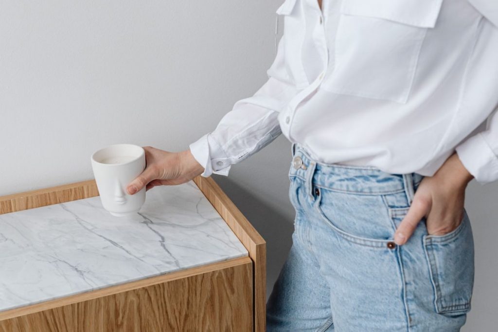 Woman in white shirt setting down coffee mug on marble table